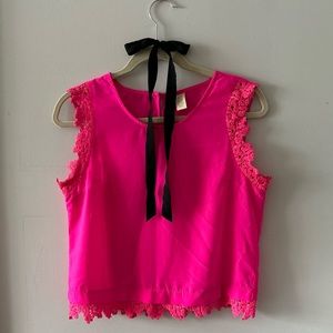 Sleeveless crew neck fuchsia top with details on sleeves and bottom.